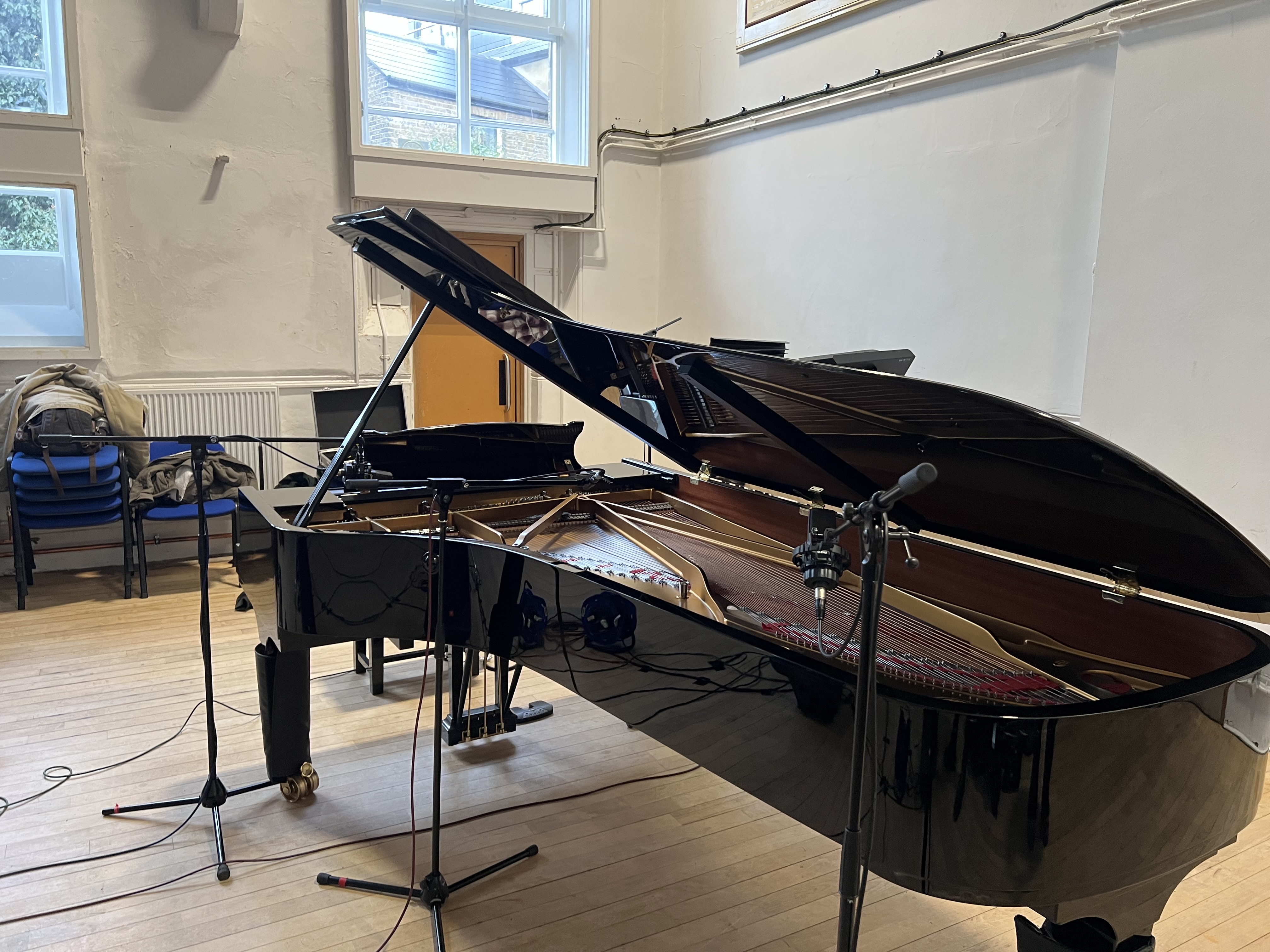 A grand piano, with multiple microphones positioned around it.