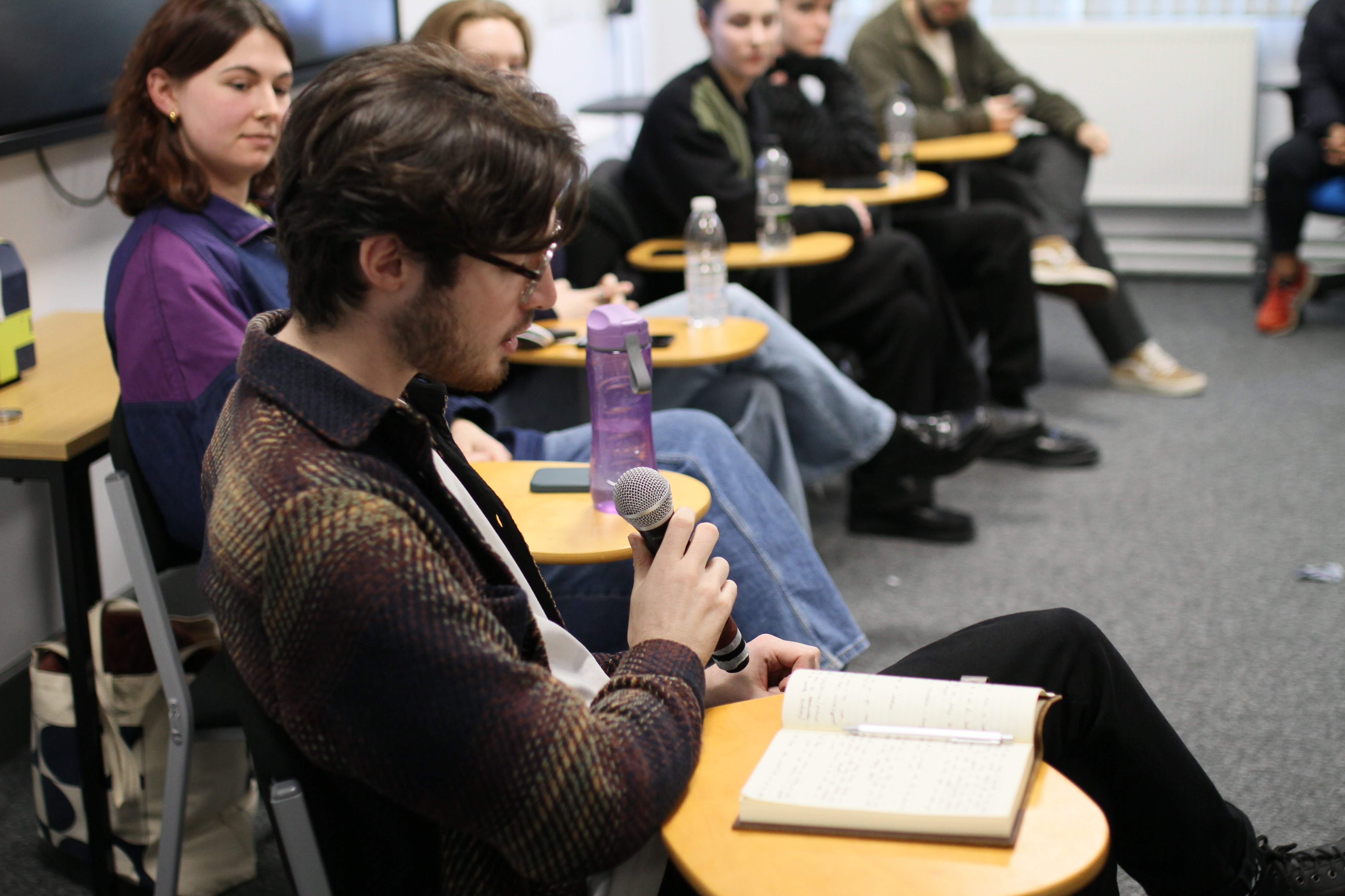 A person hosting a panel, speaking into a microphone.
